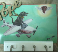 Artistic scene of a dog flying a plane chasing a winged steak, with a 'Hope' sign above.